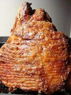 a large piece of meat sitting on top of a black grill grate next to a white wall