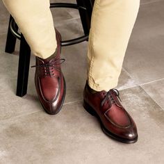 a man wearing tan pants and brown shoes standing next to a stool with his legs crossed