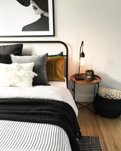 a bedroom with white walls, black and gold bedding and pictures on the wall