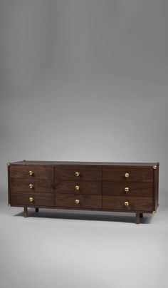 a large wooden dresser with brass handles and knobs on the top, against a gray background