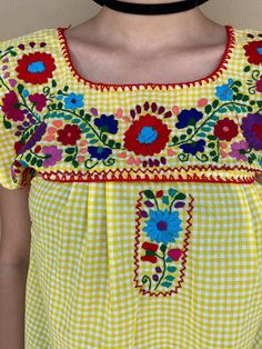 "Very rare and colorful traditional Mexican top with a twist. The gingham fabric gives the perfect modern touch that you need! Totally hand-embroidered, definitely you will be the center of attention wherever you go. Fall in love with this Picnic outfit. Loose fit Yellow and white gingham, colorful floral embroidery. Fits size SMALL Measurements taken flat: Armpit to armpit 18 1/2\" Bottom hem width 23\" Shoulder to bottom hem 25\"" Summer Gingham Blouse For Picnic, Yellow Bohemian Short Sleeve Blouse, Bohemian Yellow Short Sleeve Blouse, Summer Picnic Fitted Blouse, Fitted Summer Blouse For Picnic, Summer Short Sleeve Blouse For Picnic, Traditional Yellow Blouse For Spring, Summer Beach Peasant Top With Floral Embroidery, Multicolor Peasant Blouse For Summer