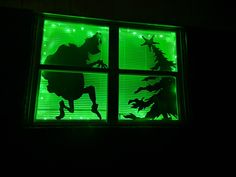 a window that has some green lights on it in the dark with silhouettes of horses and trees