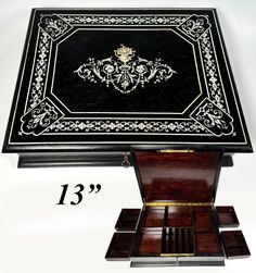 an ornate black and white box with three compartments on the bottom, one is open to reveal it's contents