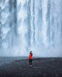 a person standing in front of a large waterfall