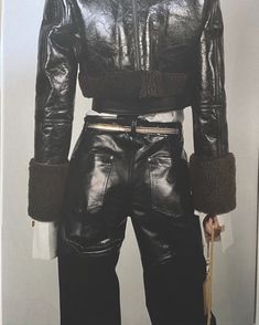 a mannequin dressed in black leather with fur collars and belted pants