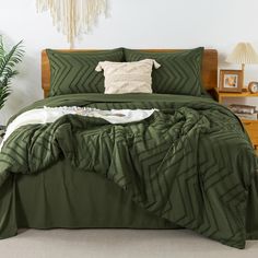 a bed with green comforter and pillows on it