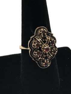 VINTAGE 14K YELLOW GOLD GARNET ART DECO RING This incredible garnet ring is crafted of 14k yellow gold and features 9 round stones. It is finished with detailed gold work. The ring is in nice vintage condition! 9 round .10ct garnets making up the shaped design. 8 Grams Size 8.5 Please message me with any questions I am open to offers : ) Shipped insured/delivery confirmation I guarantee item to be exactly as described and pictured. Antique Multi-stone Yellow Gold Cluster Ring, Antique Multi-stone Cluster Ring In Yellow Gold, Antique Gold Cluster Ring With Multi-stone, Antique Gold Cluster Ring With Gemstones, Ornate Garnet Round Rings, Ornate Round Garnet Rings, Ornate 14k Gold Collectible Ring, Vintage Gold Ruby Ring With Filigree, Victorian Gold Cluster Ring With Gemstone