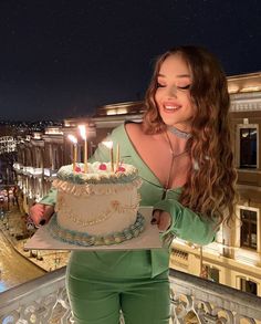 a woman holding a cake with lit candles on it