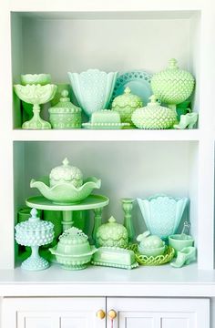 a shelf filled with lots of green vases and dishes