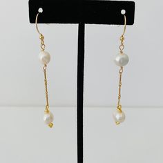 Two pearls dangle from an elegant gold chain. The chain and ear wire are gold filled. Elegant 14k Gold Filled Pearl Drop Threader Earrings, Gold Dangle Pearl Earrings With Pearl Chain, Formal 14k Gold-filled Pearl Chain Earrings, Formal 14k Gold Filled Pearl Chain Earrings, Gold Pearl Chain Dangle Earrings, Formal Pearl Chain Earrings In 14k Gold Filled, Gold Linear Earrings With Pearl Chain, Classic Gold Threader Earrings With Pearl Drop, Classic Pearl Chain Dangle Earrings