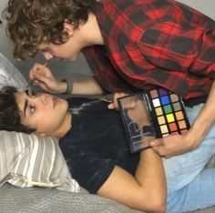 two young men laying on top of a bed with a rubix cube in front of them