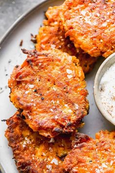 several crab cakes on a plate with a small bowl of dip