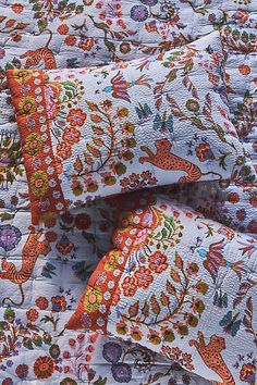 an orange and white floral quilt with matching pillows