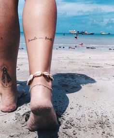 a woman's foot with a bee tattoo on it and the ocean in the background