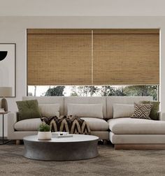 a living room filled with furniture and a window covered in bamboo shades on the windowsill