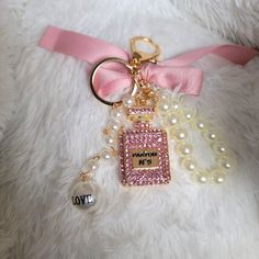 a white teddy bear with a pink bow and key chain on it's neck