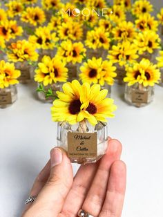 a hand holding a small jar with sunflowers in it and the words moonie written on it