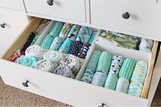 an organized drawer filled with folded towels and cloths on top of a carpeted floor