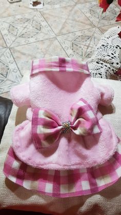 a pink and white dog coat with a bow on the collar sitting on a couch