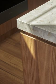 a marble counter top in a kitchen with wood flooring and wooden cabinet doors behind it