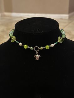 a black mannequin with a green and white necklace on it