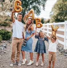 a man and two children holding up gold balloons in front of their faces with the words baby spelled out