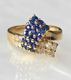 Sapphire Diamond Ring, Sapphire Ring For Women, Vintage Sapphire Ring, Sapphire Bypass Ring, Vintage Sapphire Jewelry, Valentines Day Gift A charming and feminine vintage 14k solid yellow gold ring featuring genuine blue sapphires weighing 0.61 carats and white diamonds weighing 0.26 carats intricately detailed to resemble a ribbon. *Approximate ring weight: 4.37 grams * Ring size: US 5 1/2 * Complimentary resizing is available up to 3 sizes larger or smaller than stated size. Yellow Gold Multi-stone Sapphire Ring For Anniversary, Yellow Gold Multi-stone Cluster Sapphire Ring, Yellow Gold Cluster Multi-stone Sapphire Ring, Anniversary Yellow Gold Multi-stone Sapphire Ring, Cluster Yellow Gold Hallmarked Rings, Yellow Gold Cluster Rings Hallmarked, Yellow Gold Cluster Ring In Fine Jewelry Style, Yellow Gold Cluster Ring With Hallmark, Collectible Yellow Gold Diamond Ring In Fine Jewelry Style