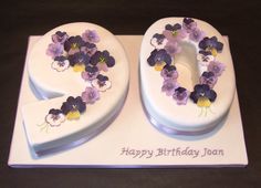 a white cake with purple and yellow flowers in the shape of the number 50 on it