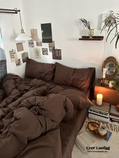 a bed with brown sheets and pillows in a room next to a table with books