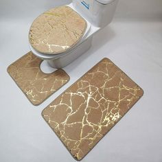 a toilet and two matching mats on a white surface with the lid up to show gold cracked paint