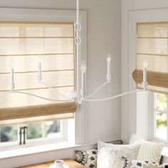 a living room filled with furniture and windows covered in roman blind shades on top of them