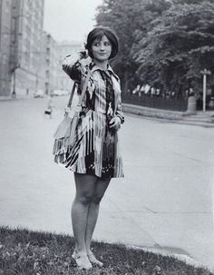 an old photo of a woman standing in the grass with her hand on her head