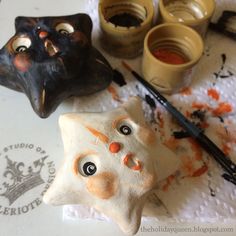 three halloween decorations sitting on top of a table next to paintbrushes and other items