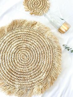 two round straw baskets sitting on top of a white bed next to an empty bottle