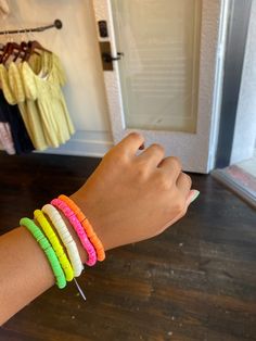 a woman's arm with several different colored bracelets on it, and a door in the background