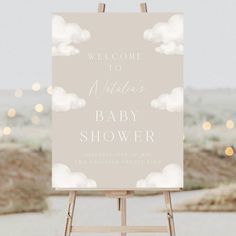 a welcome sign for a baby shower is displayed on an easel with lights in the background