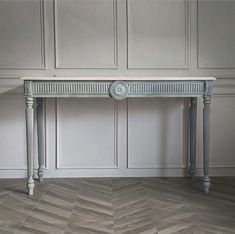 an antique console table in grey painted wood with two legs and a clock on the top