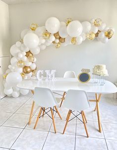 a table with white chairs and balloons on the wall