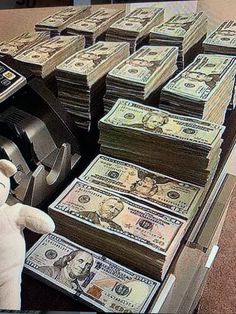 a stuffed animal sitting in front of a pile of money on top of a cash register