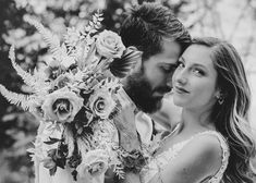 black and white photo of a bride and groom holding flowers in front of the camera