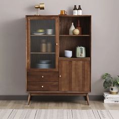 a wooden cabinet with glass doors and shelves on the top, next to a potted plant