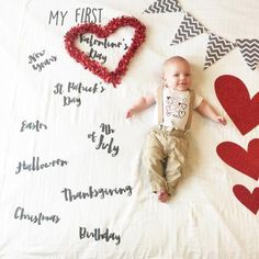 a baby laying on top of a bed next to valentine's day signs and hearts