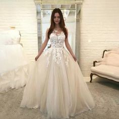 a woman standing in front of a mirror wearing a wedding dress