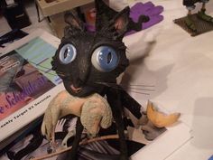 a cat figurine sitting on top of a table next to a pile of books