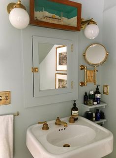 a white sink sitting under a bathroom mirror next to a wall mounted faucet