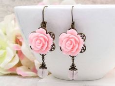 "These are romantic vintage inspired light pink rose earrings. They feature beautiful pink resin roses on top of brass floral filigrees and paired with natural rose quartz beads. They hang underneath leverback earrings. The earrings measure about 56mm (2.2 inches) from the top of the ear wire to the bottom of the pearl. They are perfect for occasions, a wonderful idea for gift giving and as a little treat for yourself. Your earrings will presented in a gift box and tied with ribbon. Measurements Rose-colored Flower Earrings For Valentine's Day, Rose Flower Earrings For Valentine's Day Wedding, Vintage Pink Flower-shaped Earrings, Pink Flower Earrings With Rose Design, Pink Flower Jewelry With Rose Design, Pink Elegant Flower Earrings For Valentine's Day, Pink Rose Design Flower Earrings For Valentine's Day, Feminine Pink Jewelry With Rose Design, Elegant Pink Flower Earrings For Valentine's Day