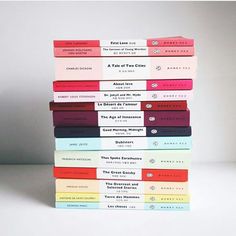 a stack of books sitting on top of each other in front of a white wall