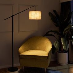 a living room with a chair, lamp and potted plant