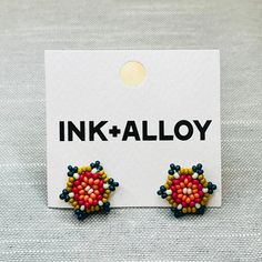 two pairs of colorful beaded earrings sitting on top of a white card with the words ink - alloy