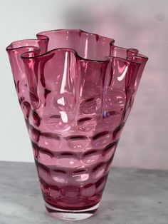 a pink glass vase sitting on top of a table